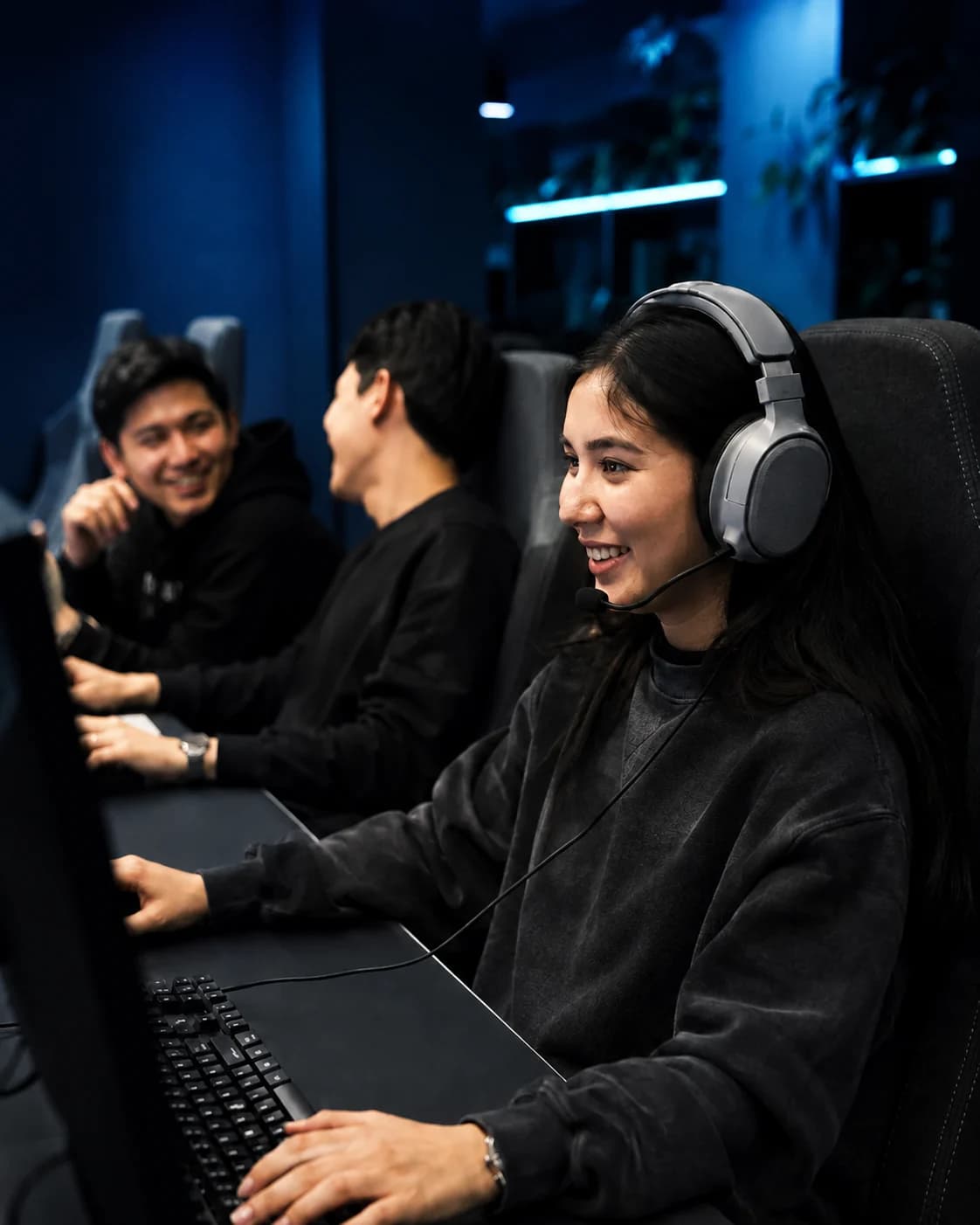 Three friends enjoying a game together at neighboring PCs in a gaming club.