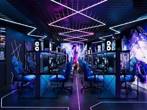 A symmetrical gaming room with rows of computers and ceiling lights.