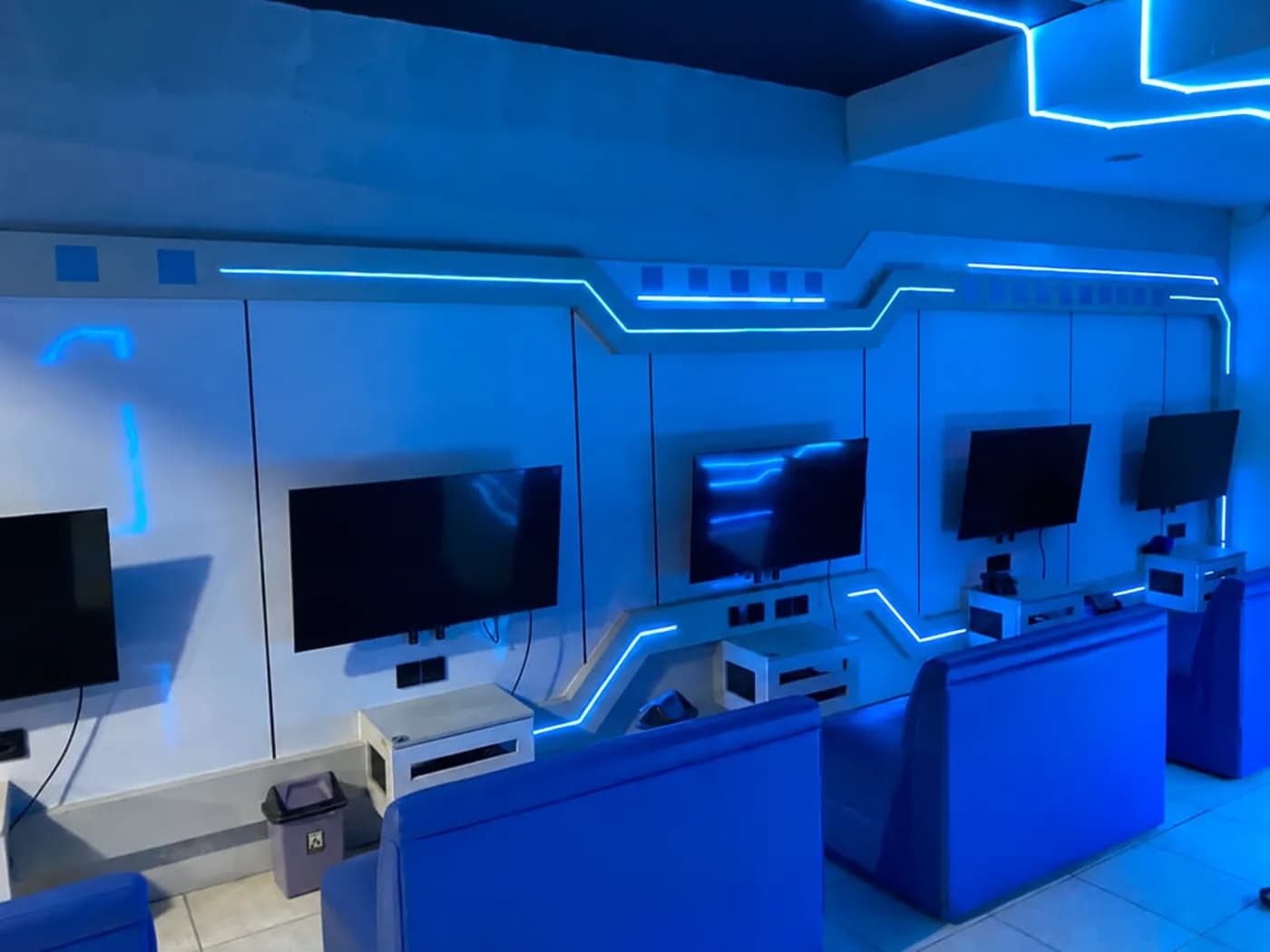 A blue-lit console area with screens and lounge seating.