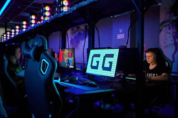 A player at a computer in a dark gaming club.